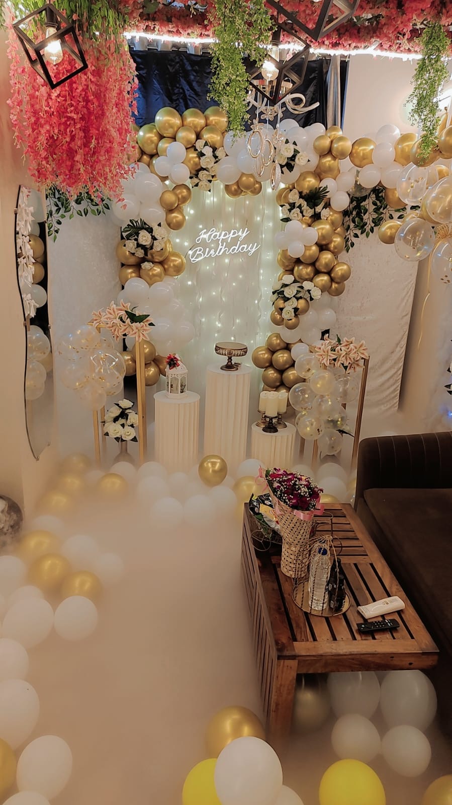Birthday cabana setup with gold balloons and neon sign